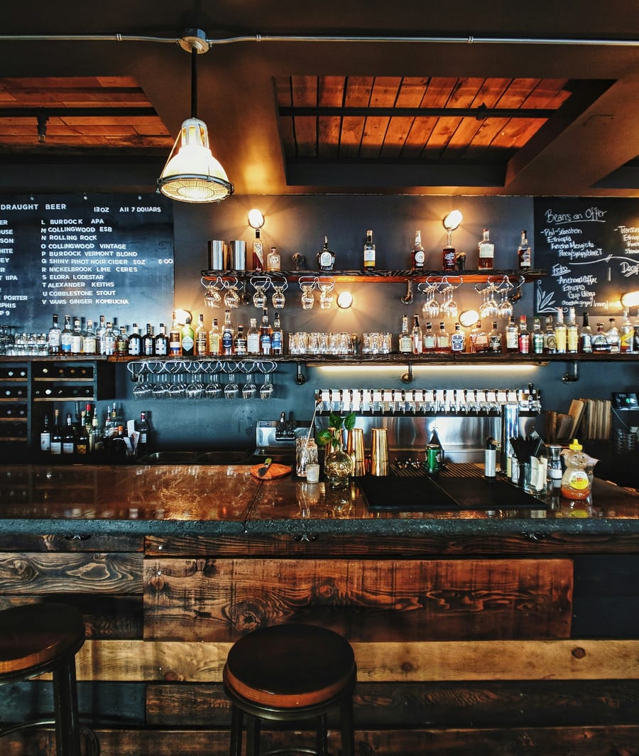 Interior de un bar con la barra servida y las sillas vacías, antes de abrir.